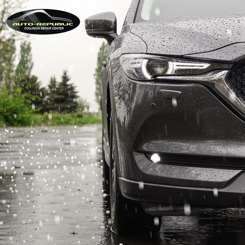 A black car is parked on a wet road in the rain