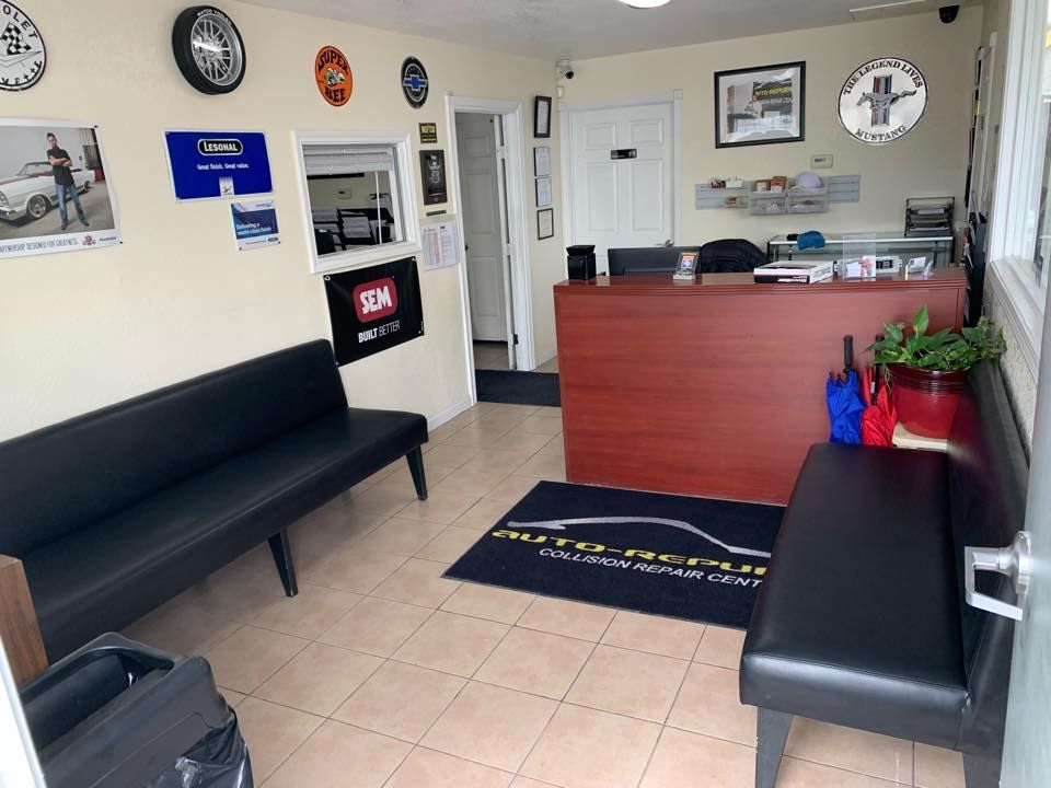 A waiting room in a car dealership with a couch and a desk