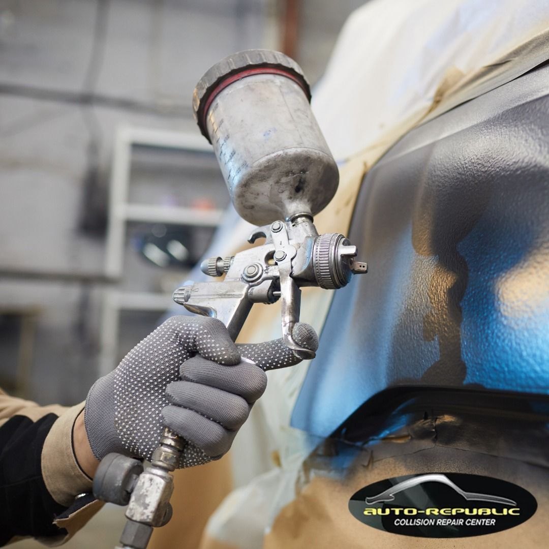 A person is spray painting a car with an auto republic logo in the background