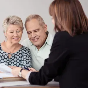 Older couple reviewing documents with a professional, possibly a financial advisor.
