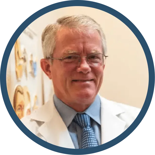 Man in a white coat and glasses, smiling, inside a blue-rimmed circle.