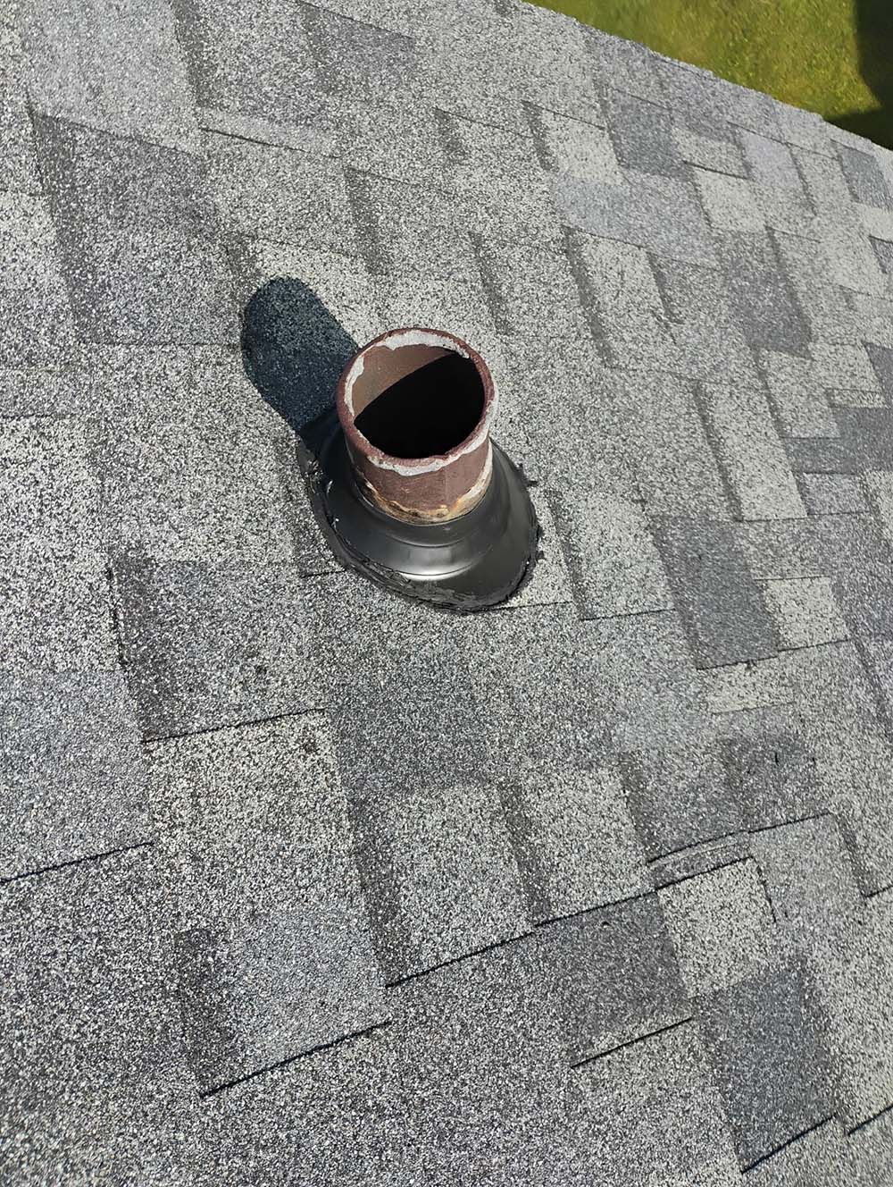 Roof vent pipe protruding from asphalt shingle roof.