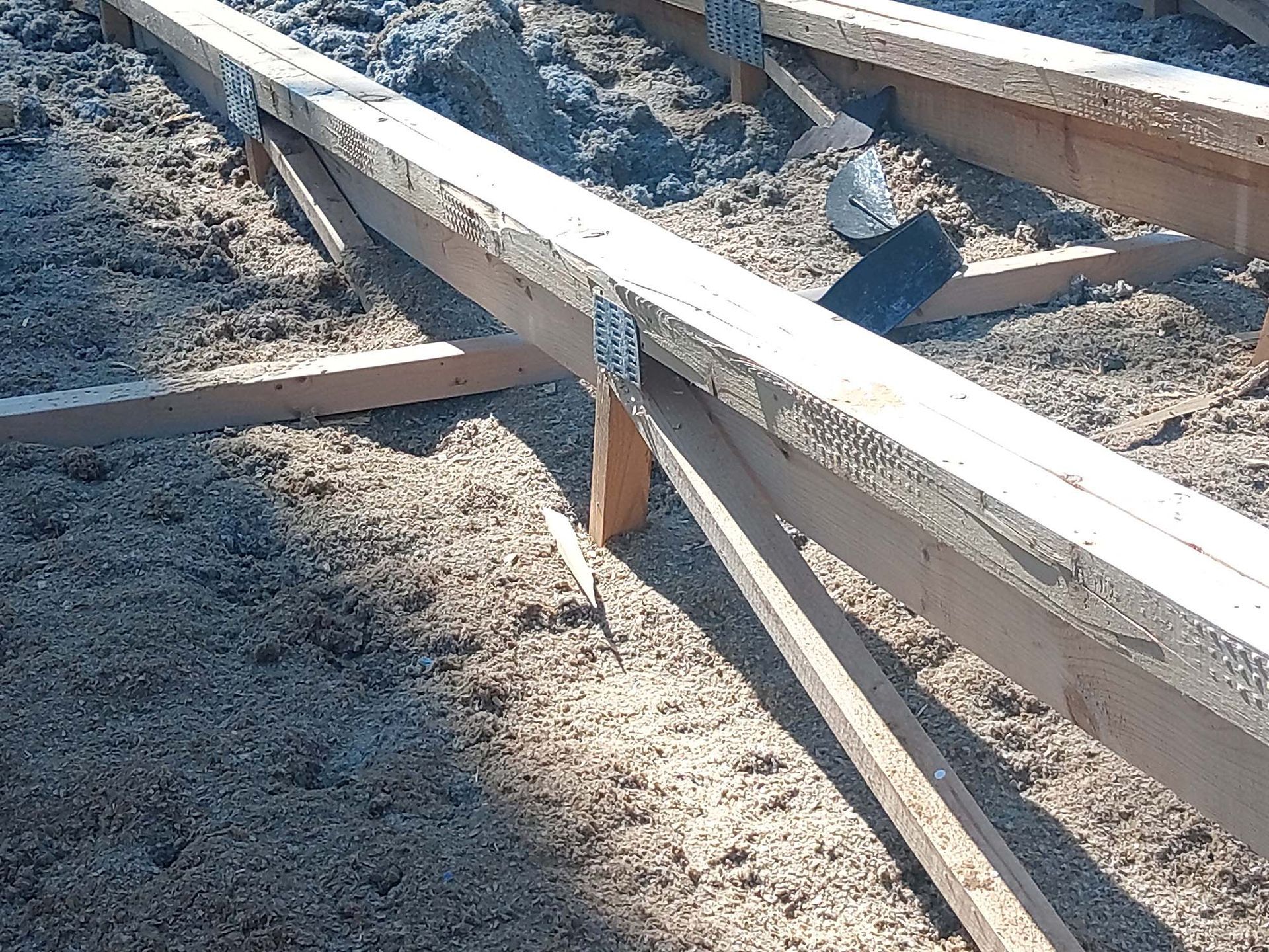 Wooden joists and support beams, partly covered with insulation, in a construction setting.