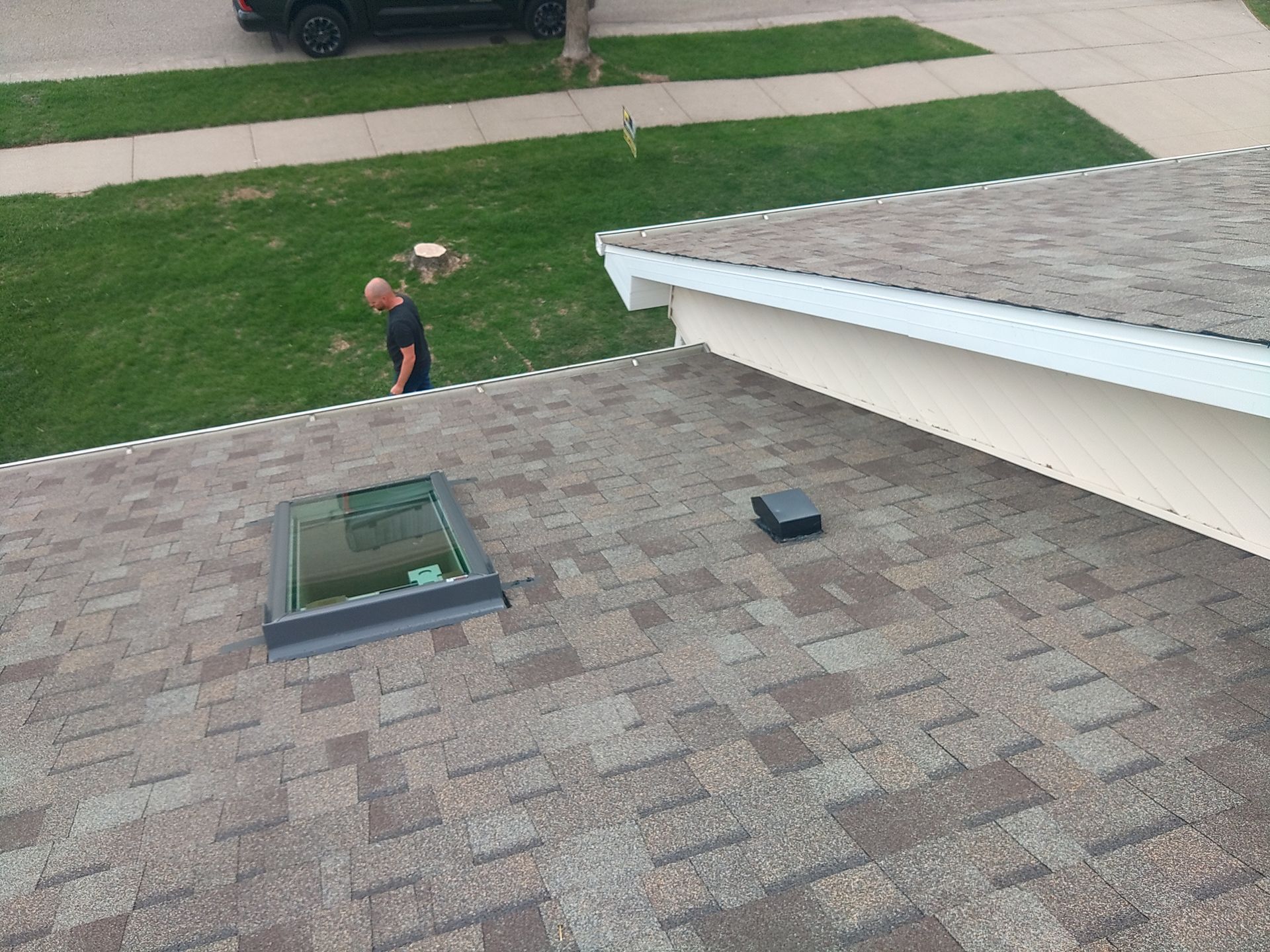 Rooftop with a skylight and a vent, person walking on the grass.