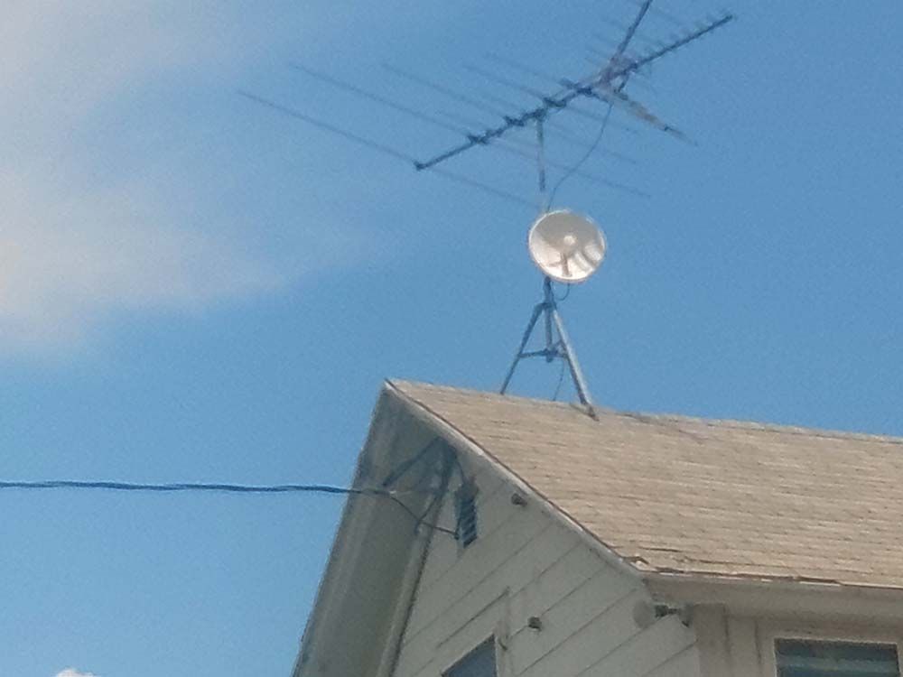 Television antennas on a house roof against a partly cloudy sky.