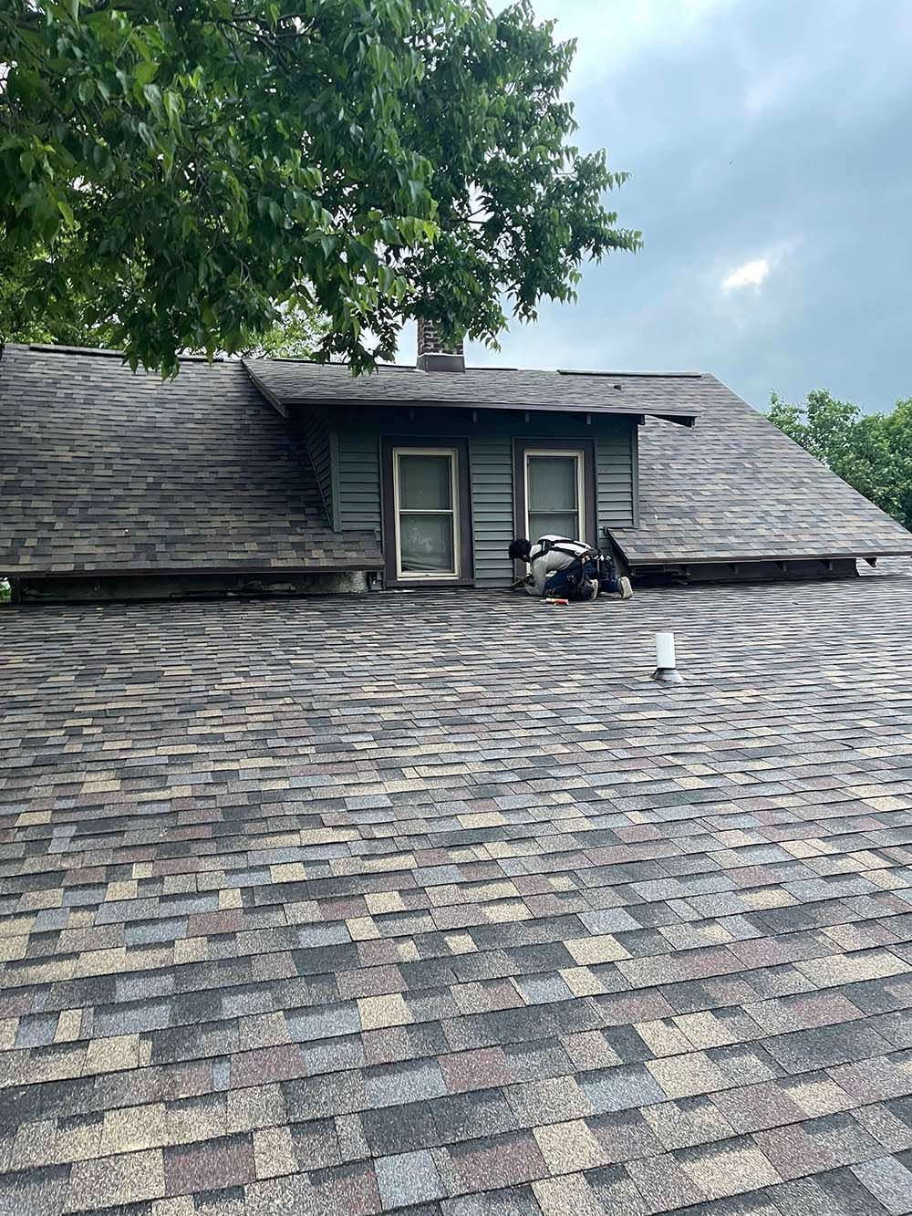 A weathered roof with a dormer and chimney, under an overcast sky.