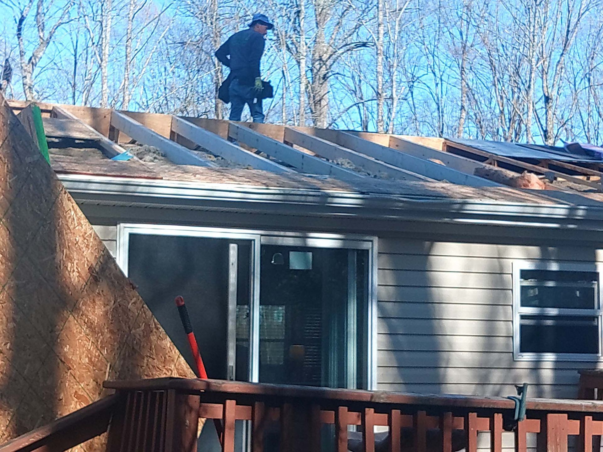 Roofer on a house roof installing new supports. Daytime, outdoors.