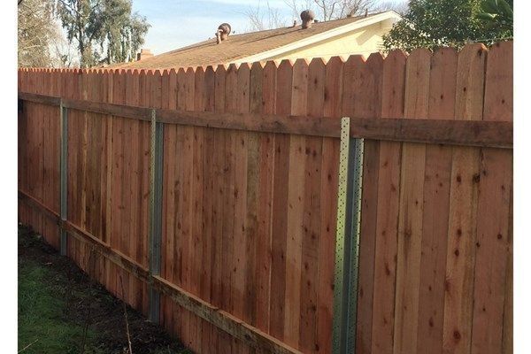 Wooden fence with metal posts, view of backyard.