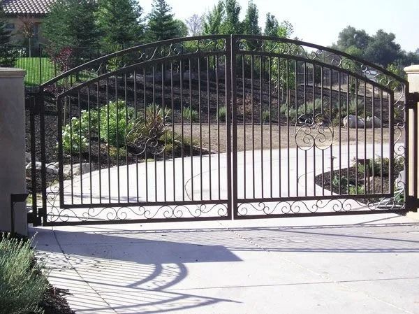 Iron driveway gate with arched top and scrollwork details.