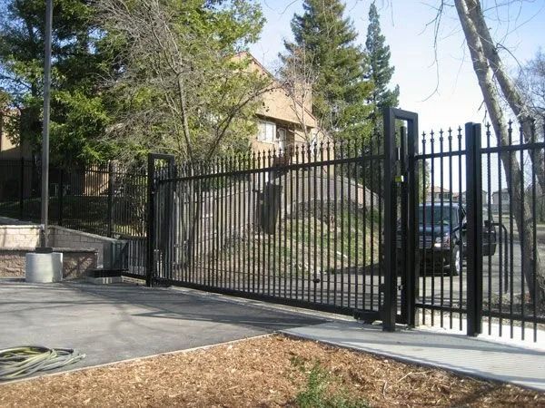Black metal security gate at a paved entrance to a building.