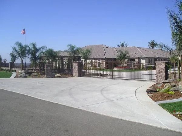 Large brick home with gate and driveway on a sunny day.