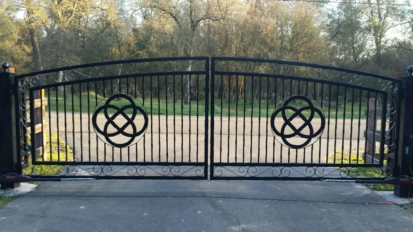 Black metal driveway gates with decorative Celtic knots.