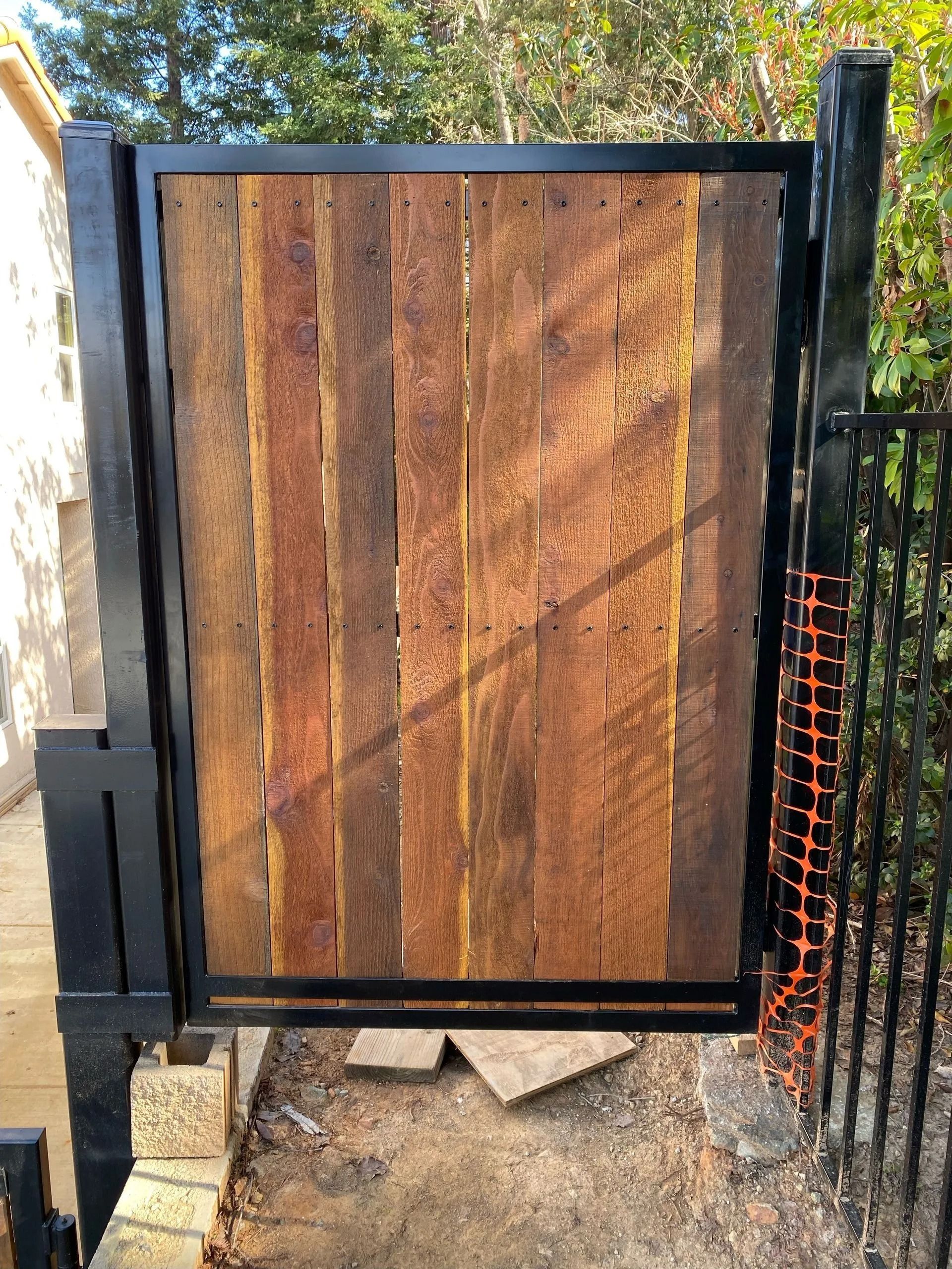 Black metal gate with vertical wood planks.