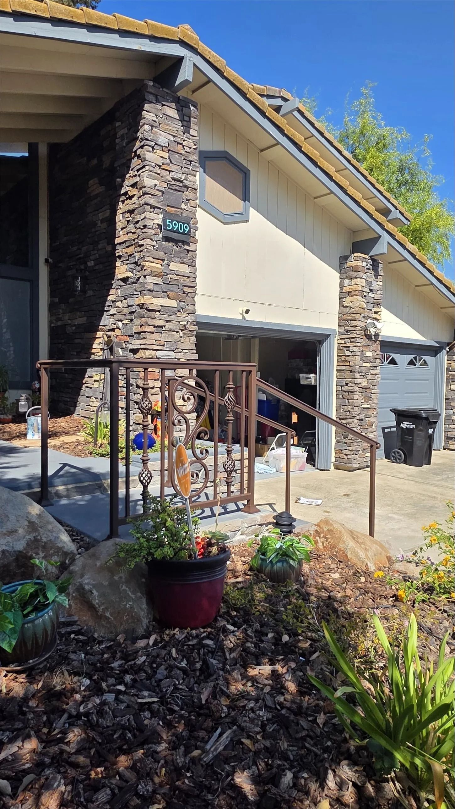Exterior of a house with stone accents, a garage, and an ornate metal railing.