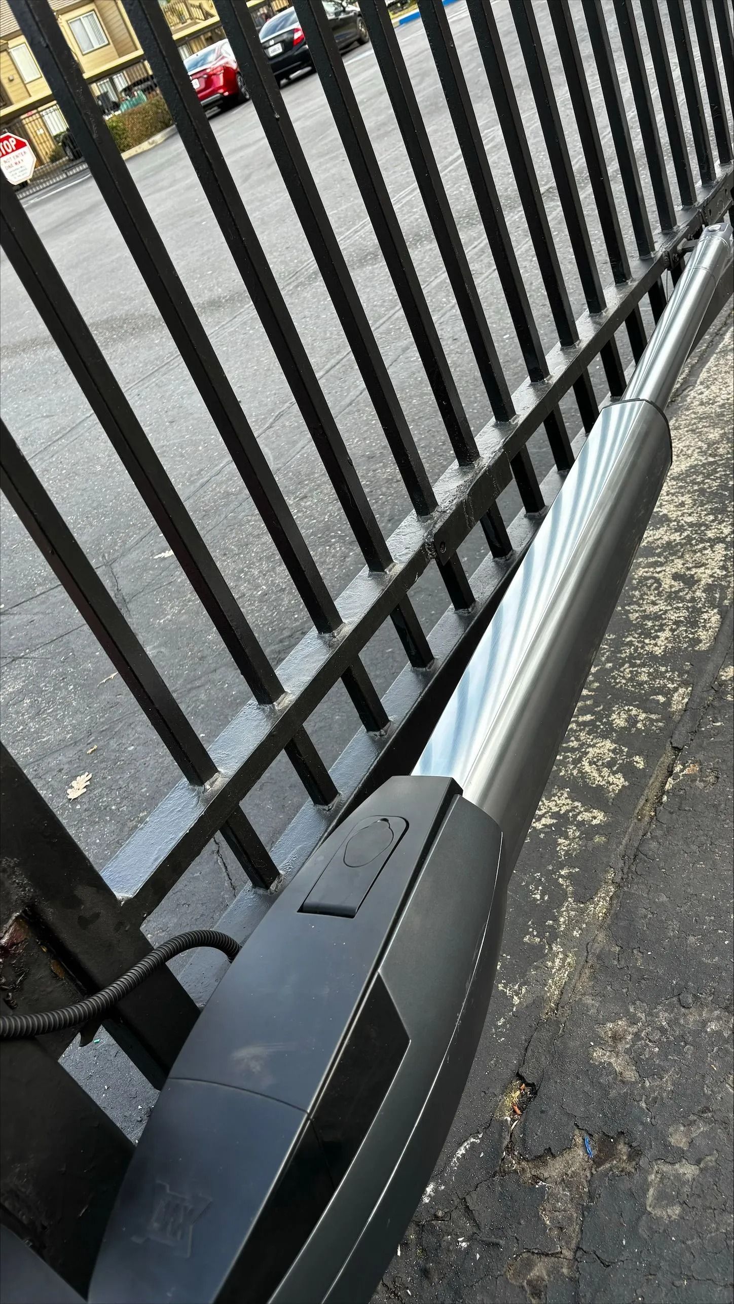 A black metal security gate with an attached automatic gate opener.