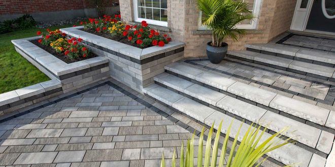 Stone steps and flower beds leading to a home with a palm tree in a pot.
