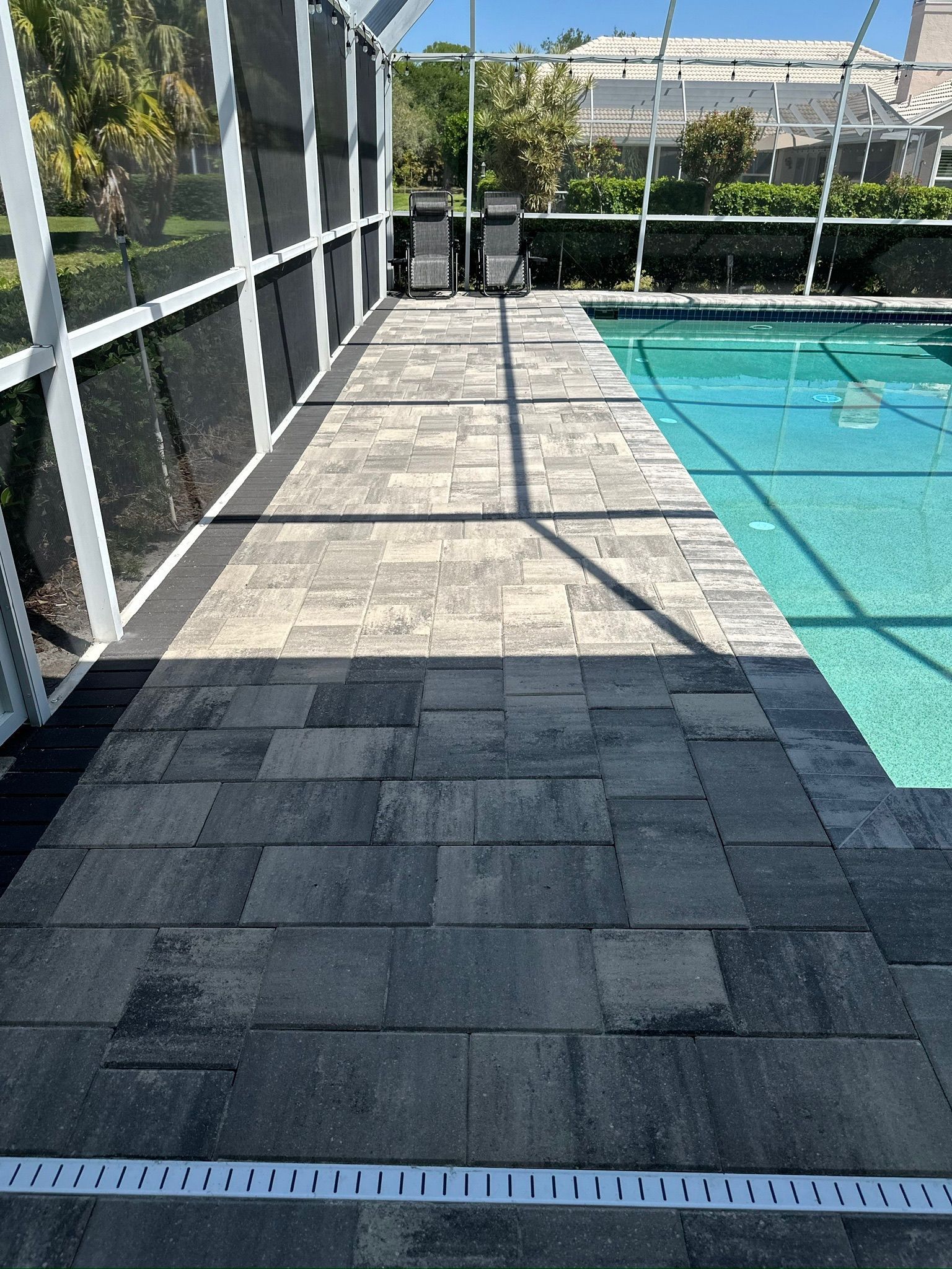 Poolside patio with gray pavers and a screened enclosure.