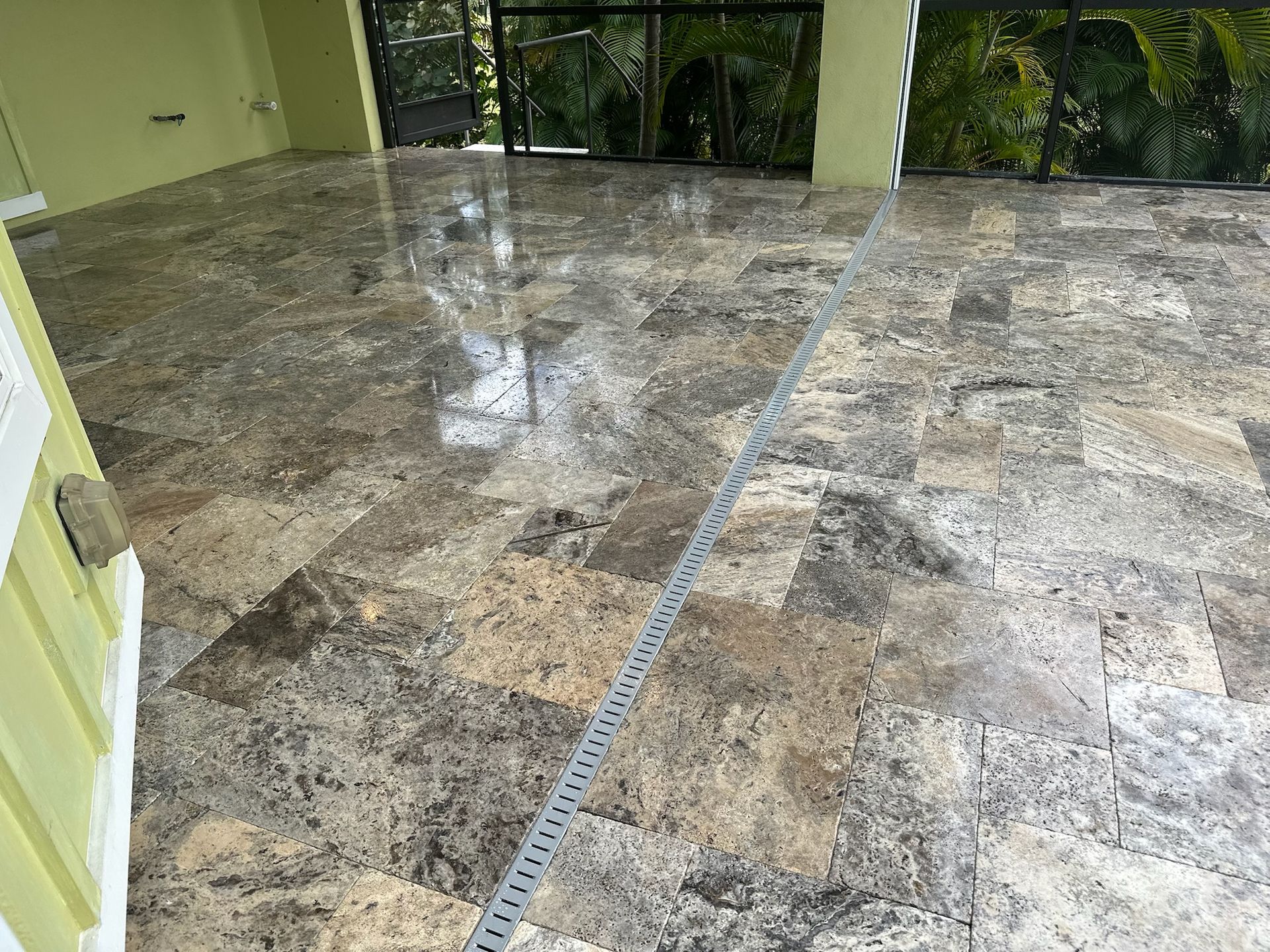Polished stone floor, light brown and gray with black accents.  A drainage channel runs across the floor.