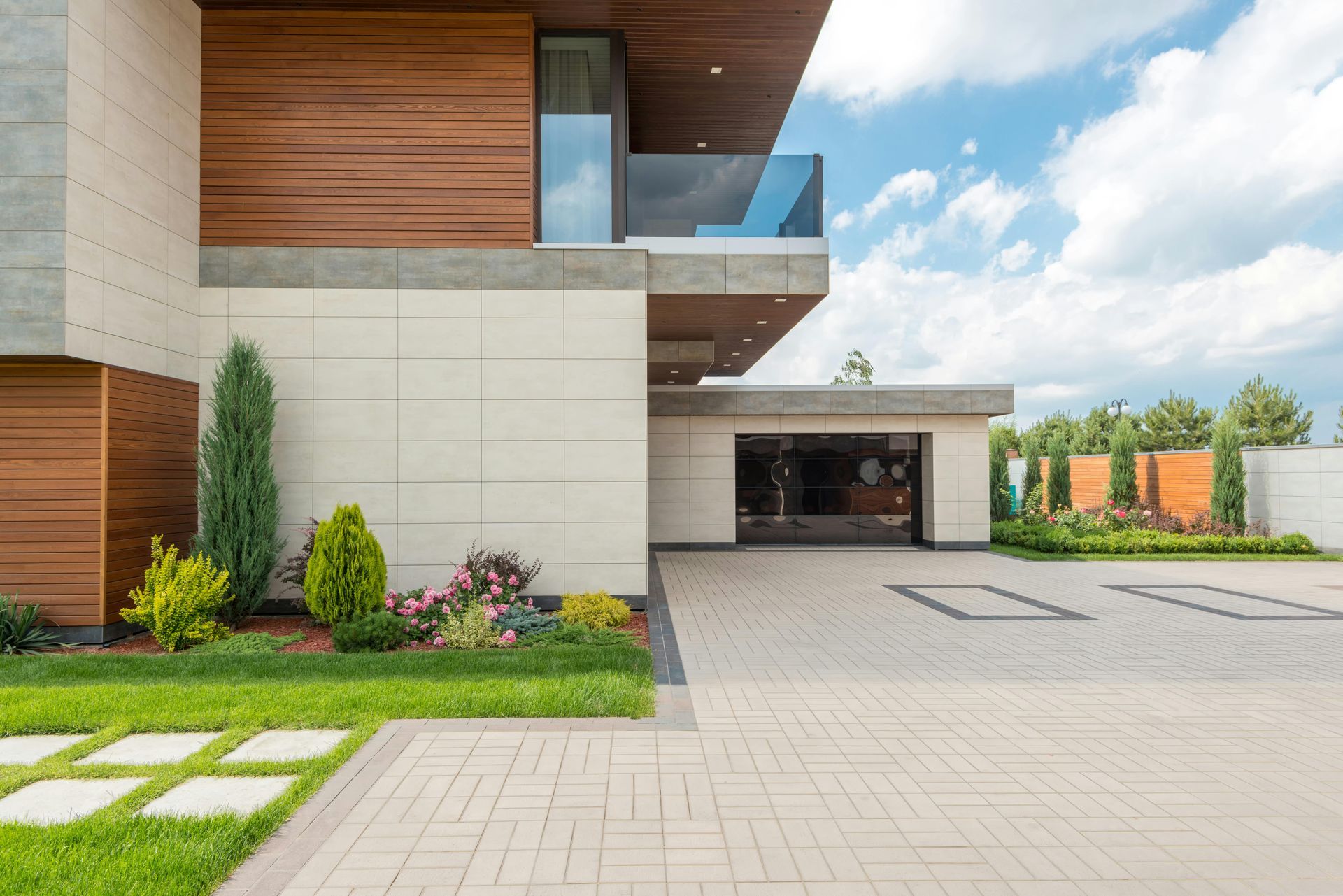 Modern home exterior with a driveway, garage, and landscaping under a blue sky.