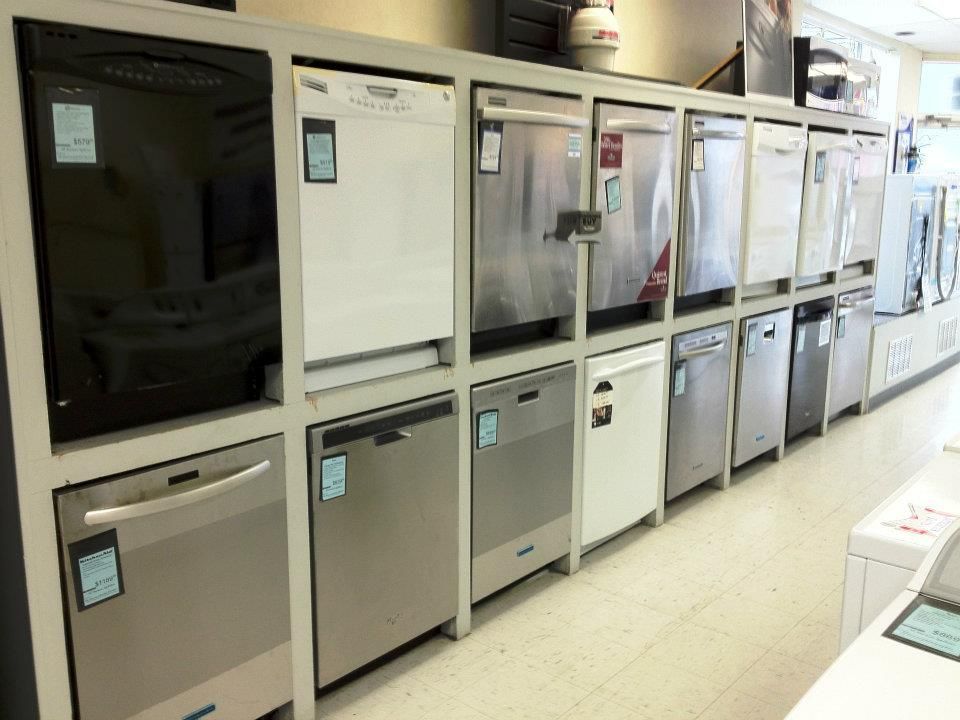 Rows of dishwashers on display in a store, various colors and models.