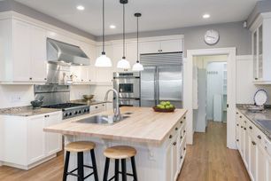 A kitchen with white cabinets , wooden counter tops and stainless steel appliances