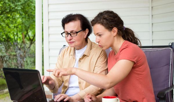 Two men are sitting at a table looking at a book.