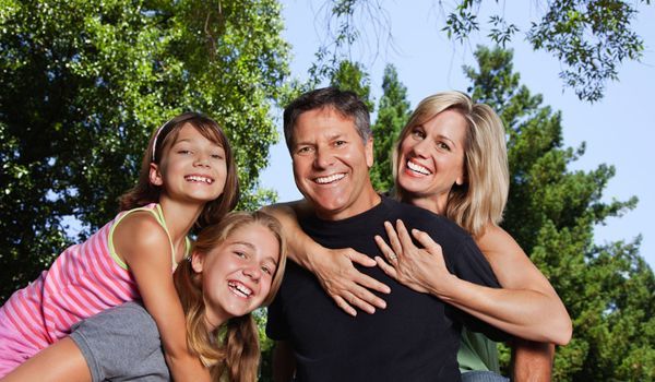 A family is posing for a picture together in a park.