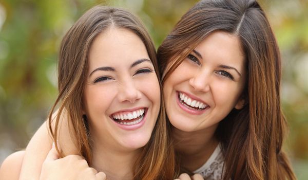 A man and a woman are sitting at a table looking at a tablet.