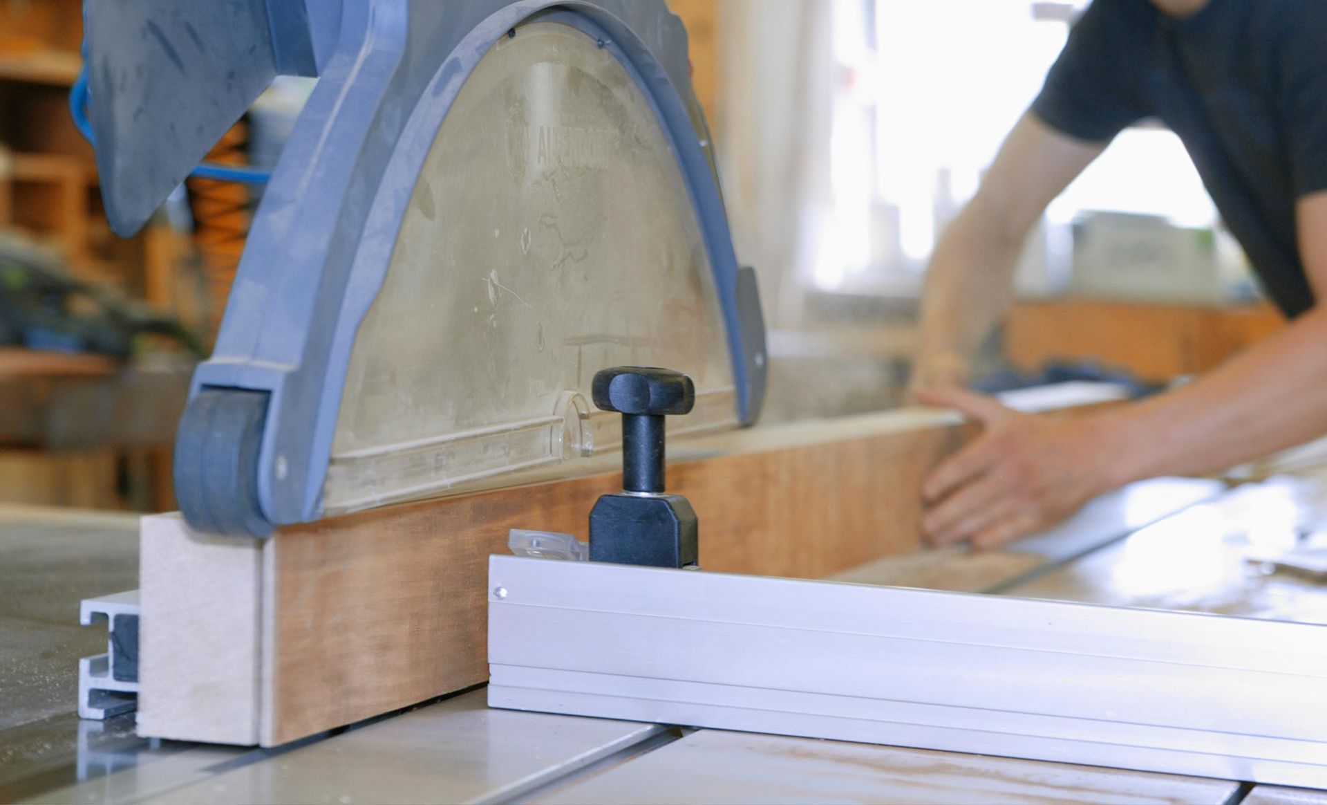 Woodworking clamp securing a light wood board in a workshop