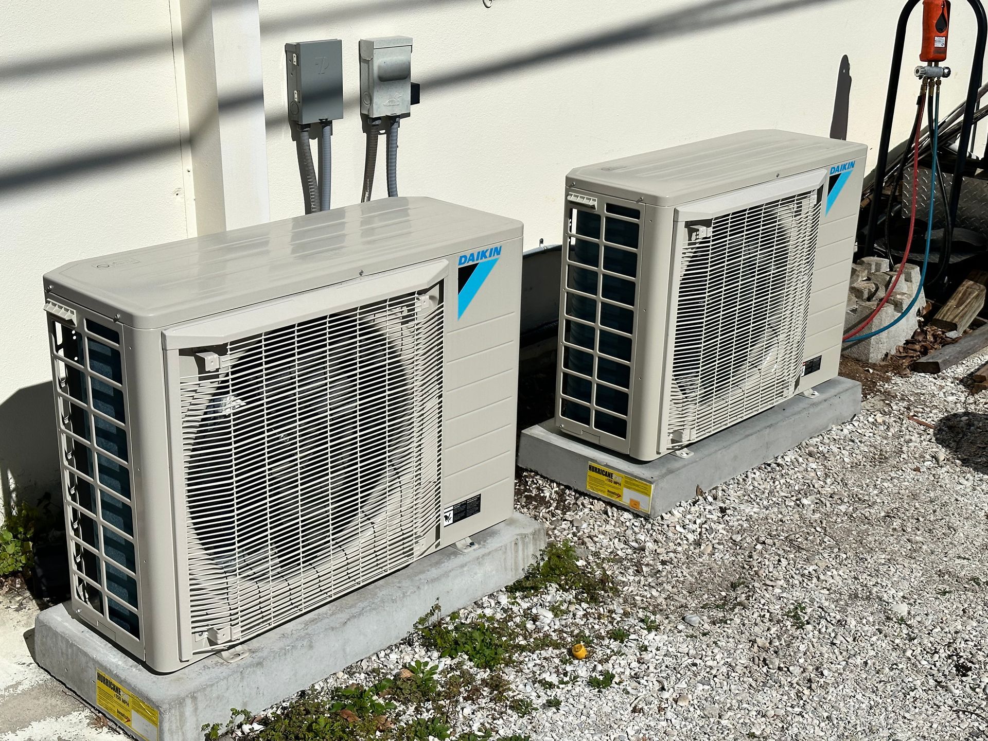 Two air conditioners are sitting next to each other outside of a building.