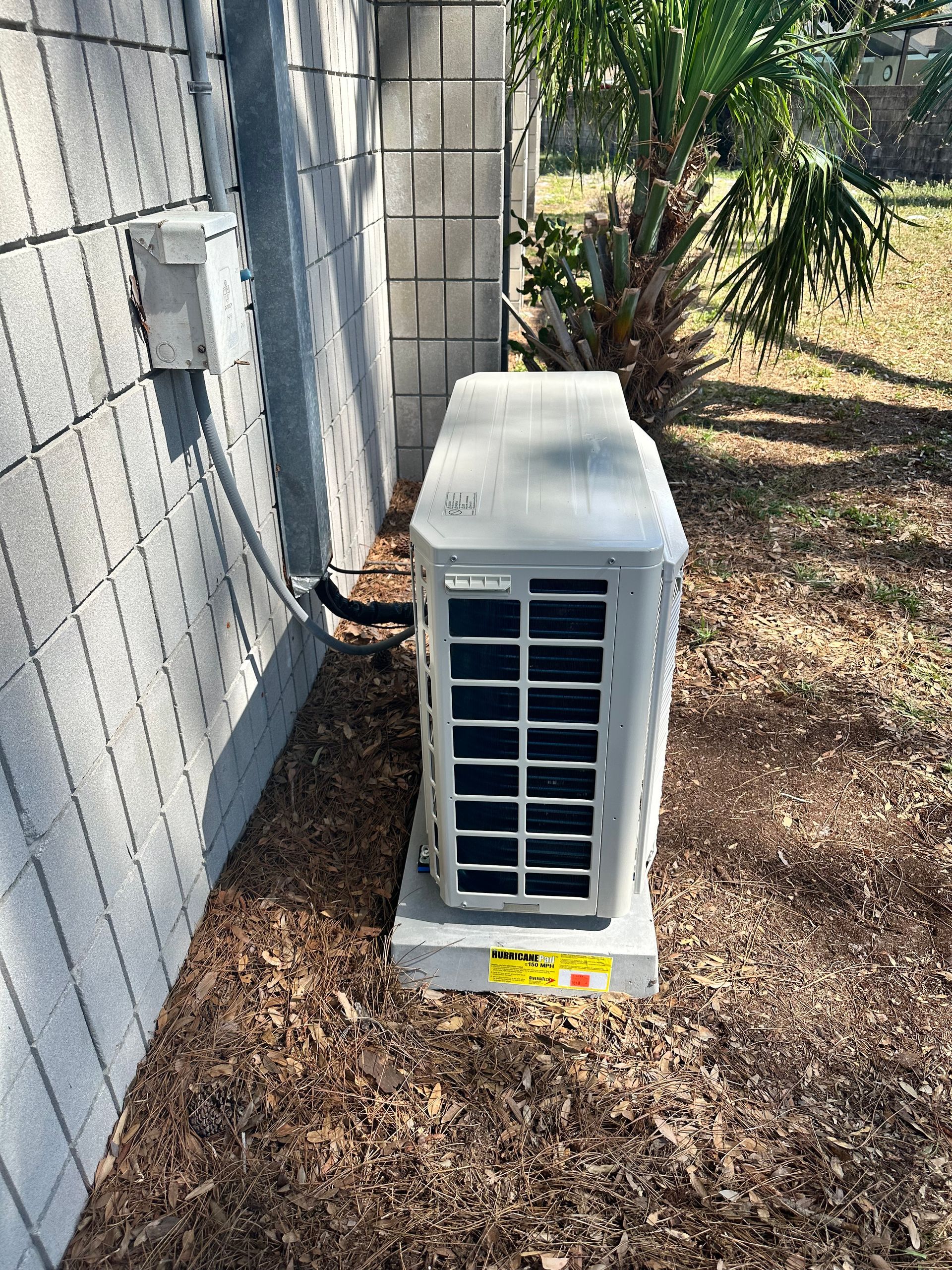 A white air conditioner is sitting on the side of a building.