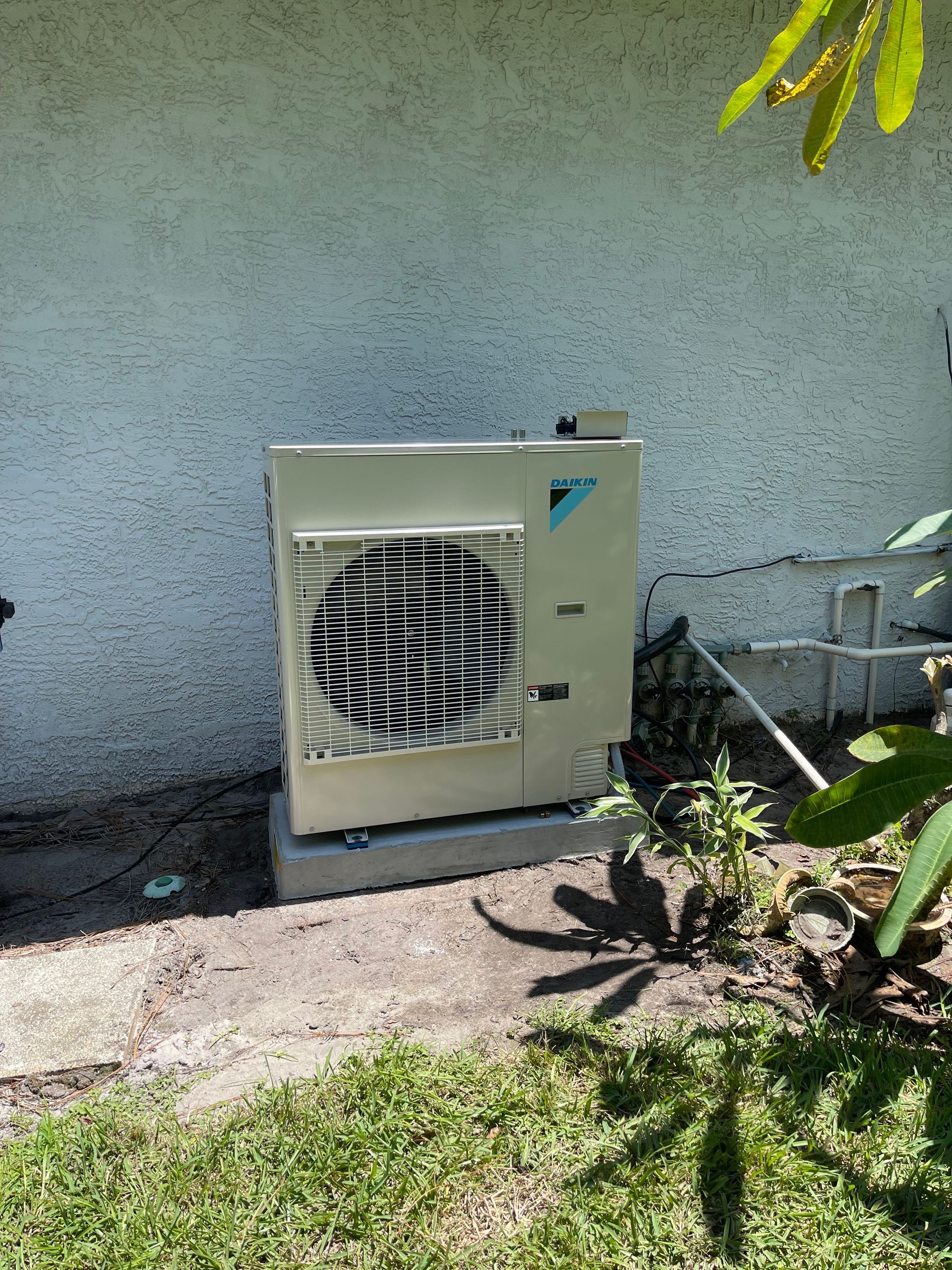 A white air conditioner is sitting on the ground in front of a white wall.