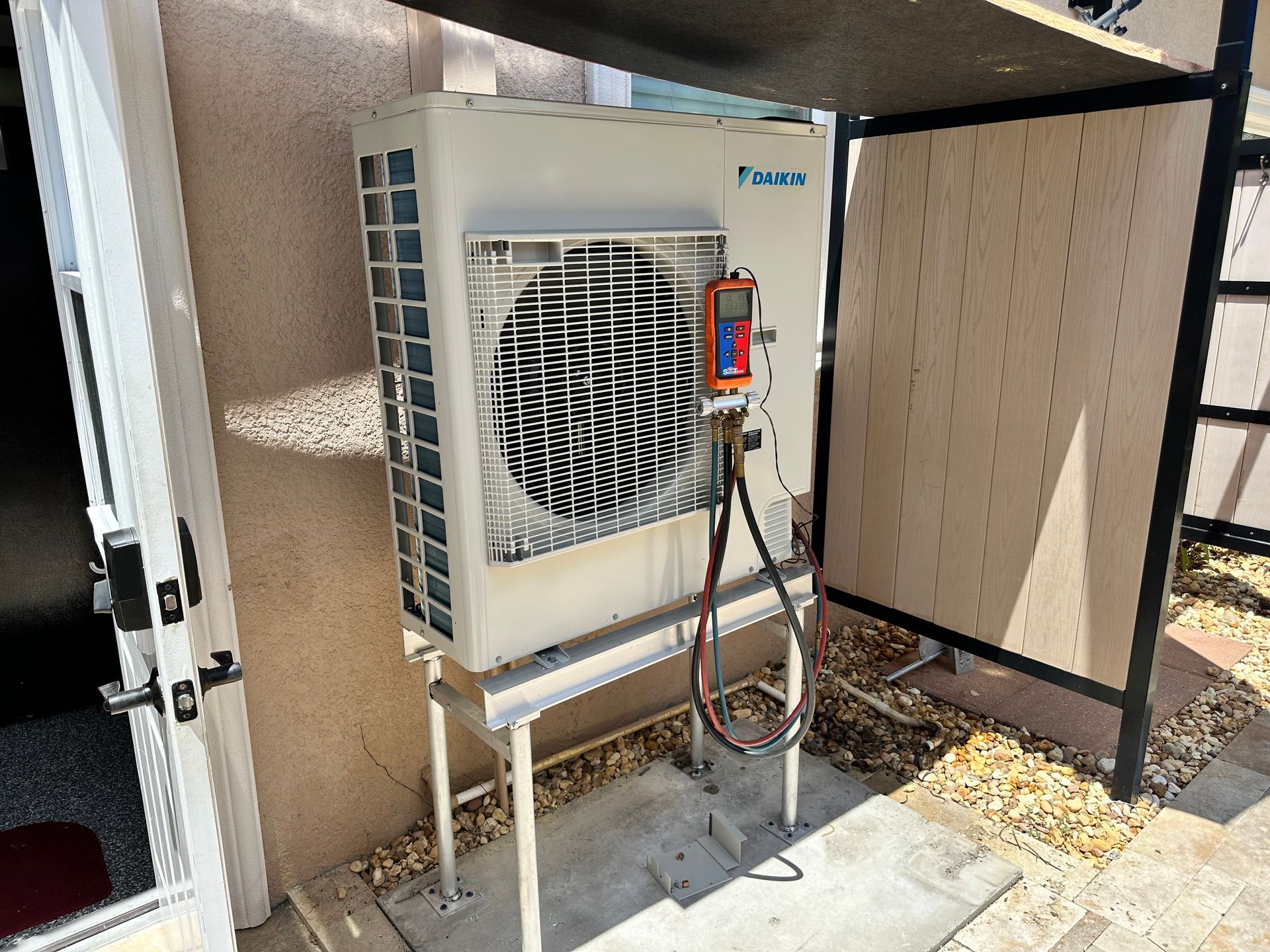 A white air conditioner is sitting on a stand outside of a building.