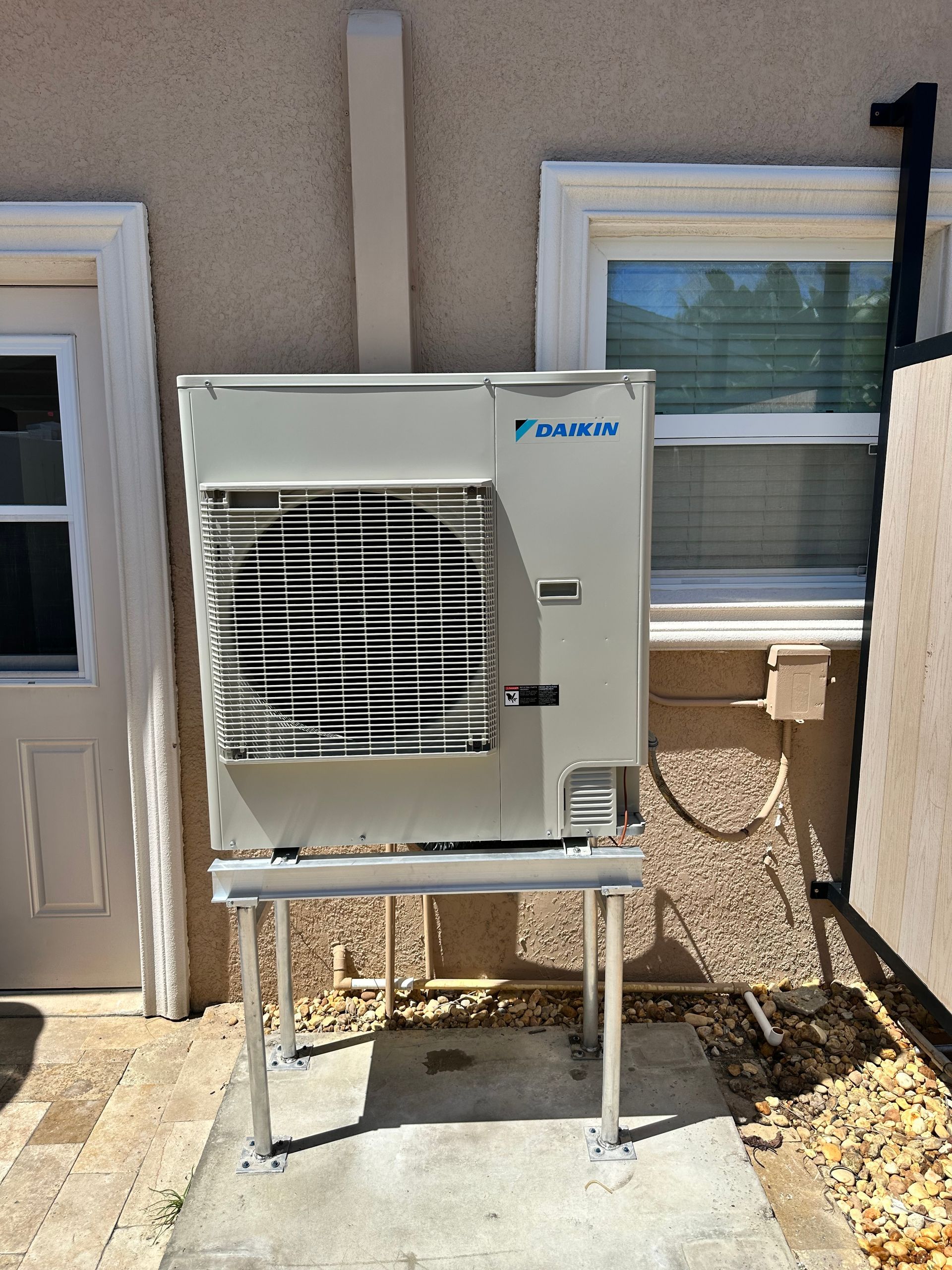 A large air conditioner is sitting outside of a building next to a window.