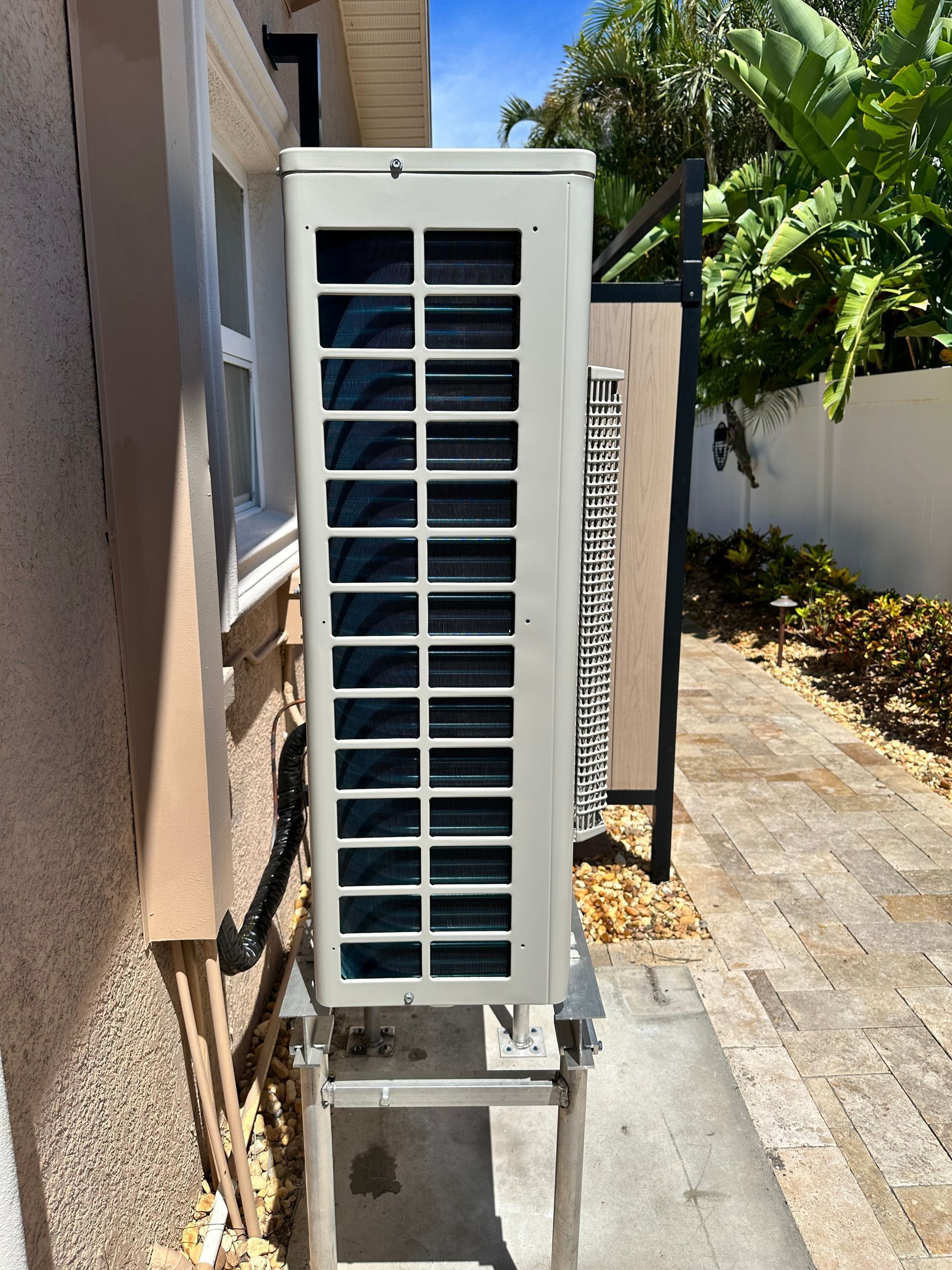 A large white air conditioner is sitting outside of a house.