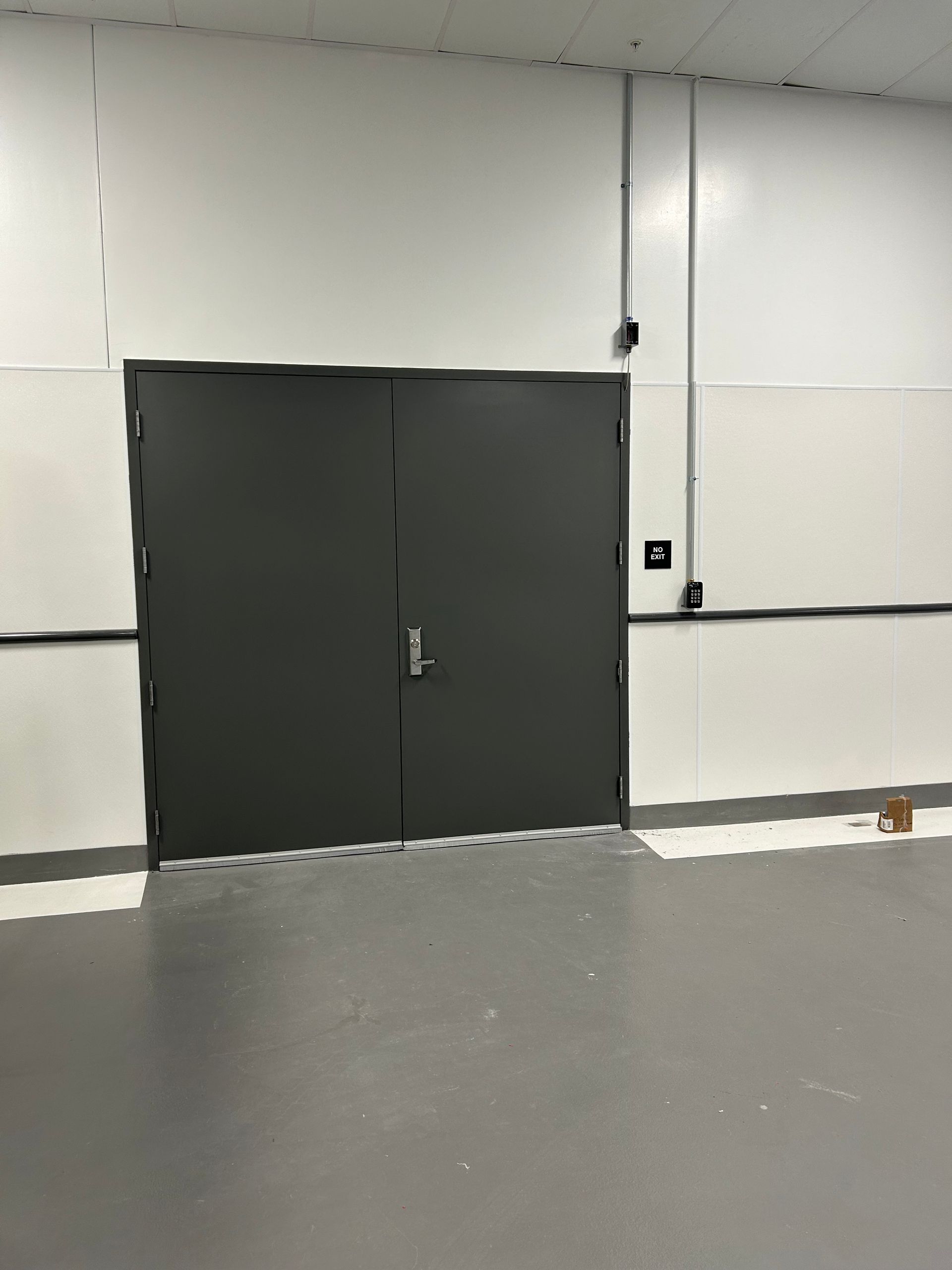 Gray double doors in a white room with gray flooring and black trim.