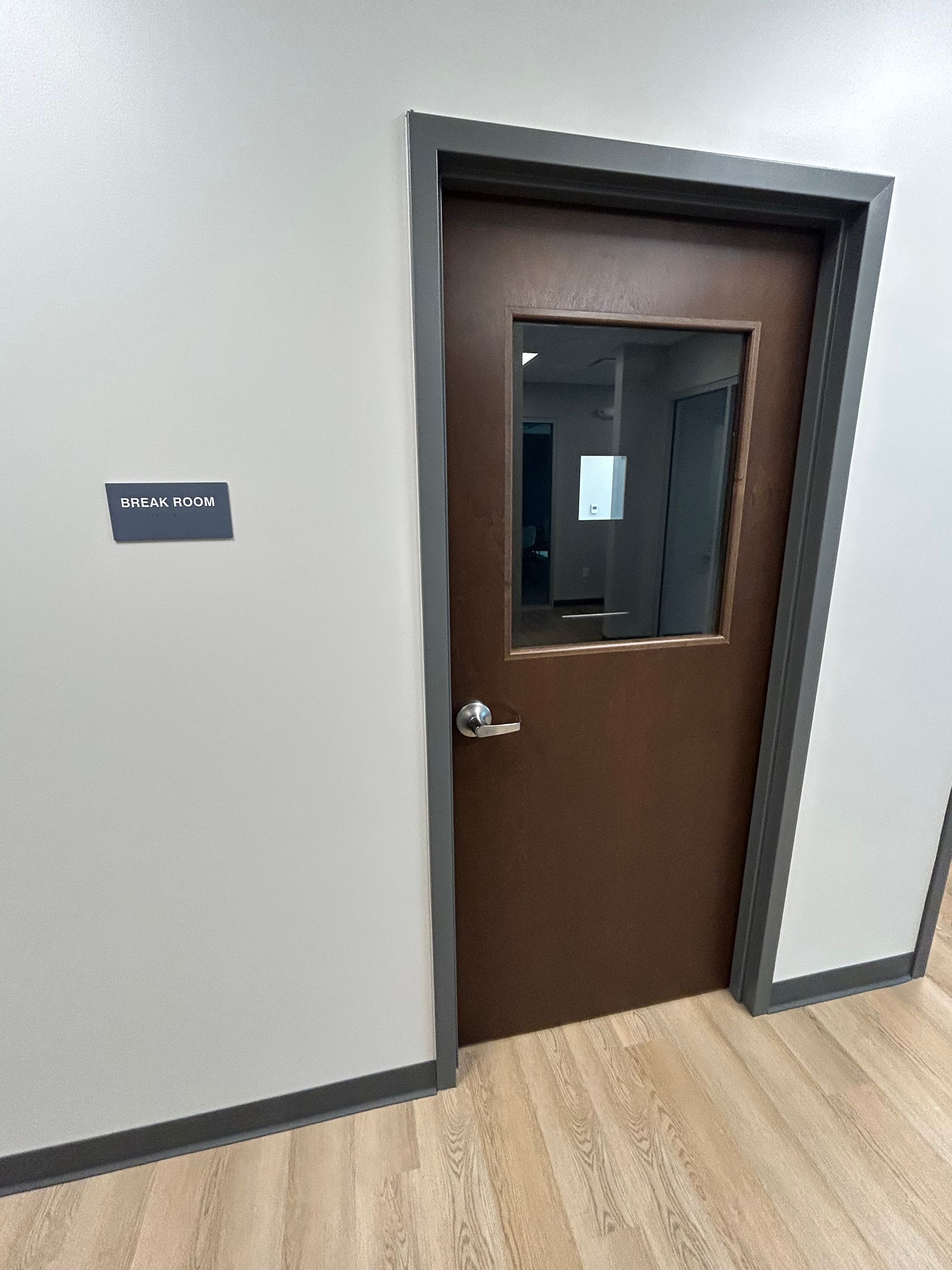 Brown door with window, gray frame, and a sign that says 