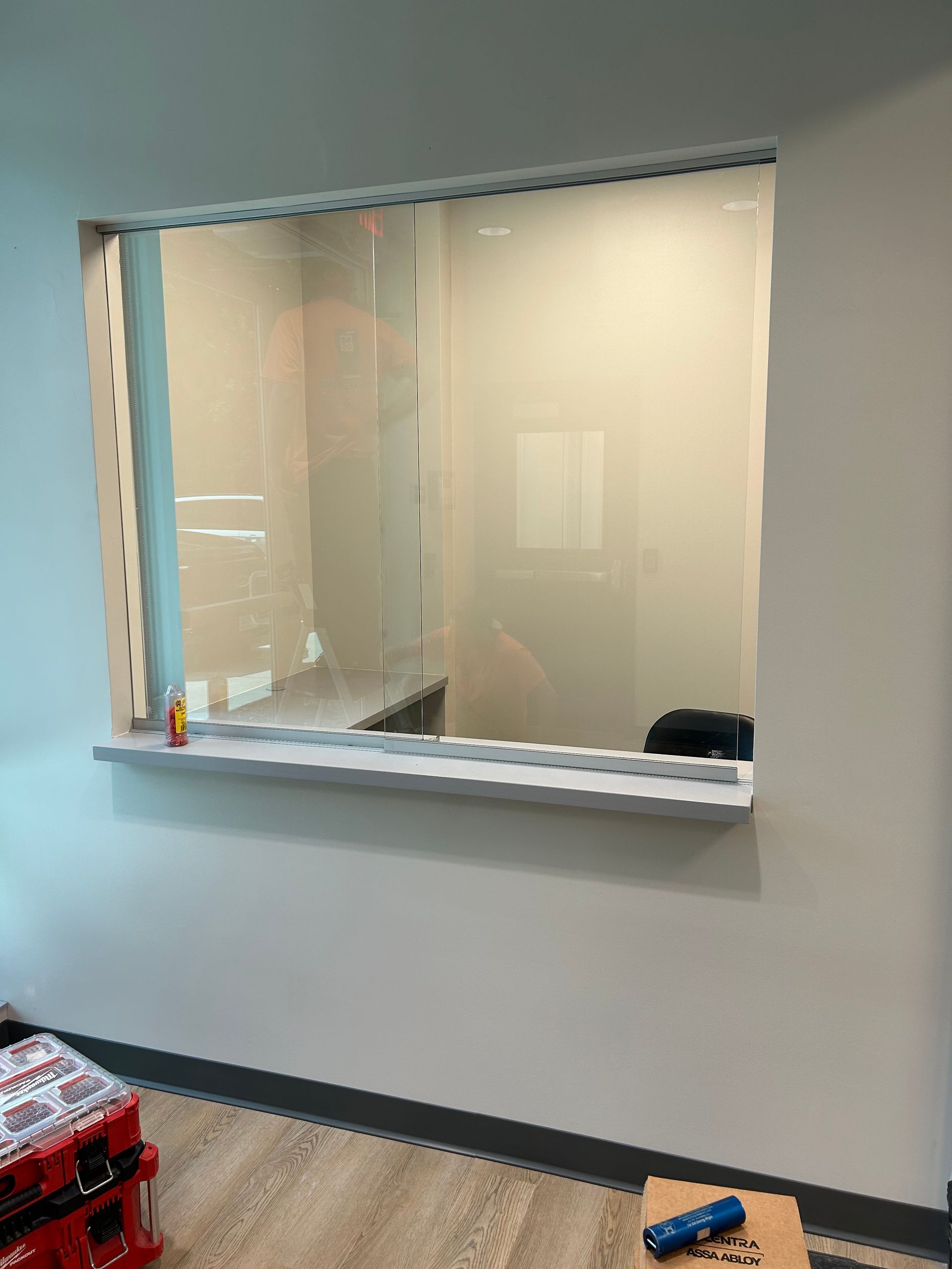 A window with a clear plastic barrier, counter space, and a work area visible inside.