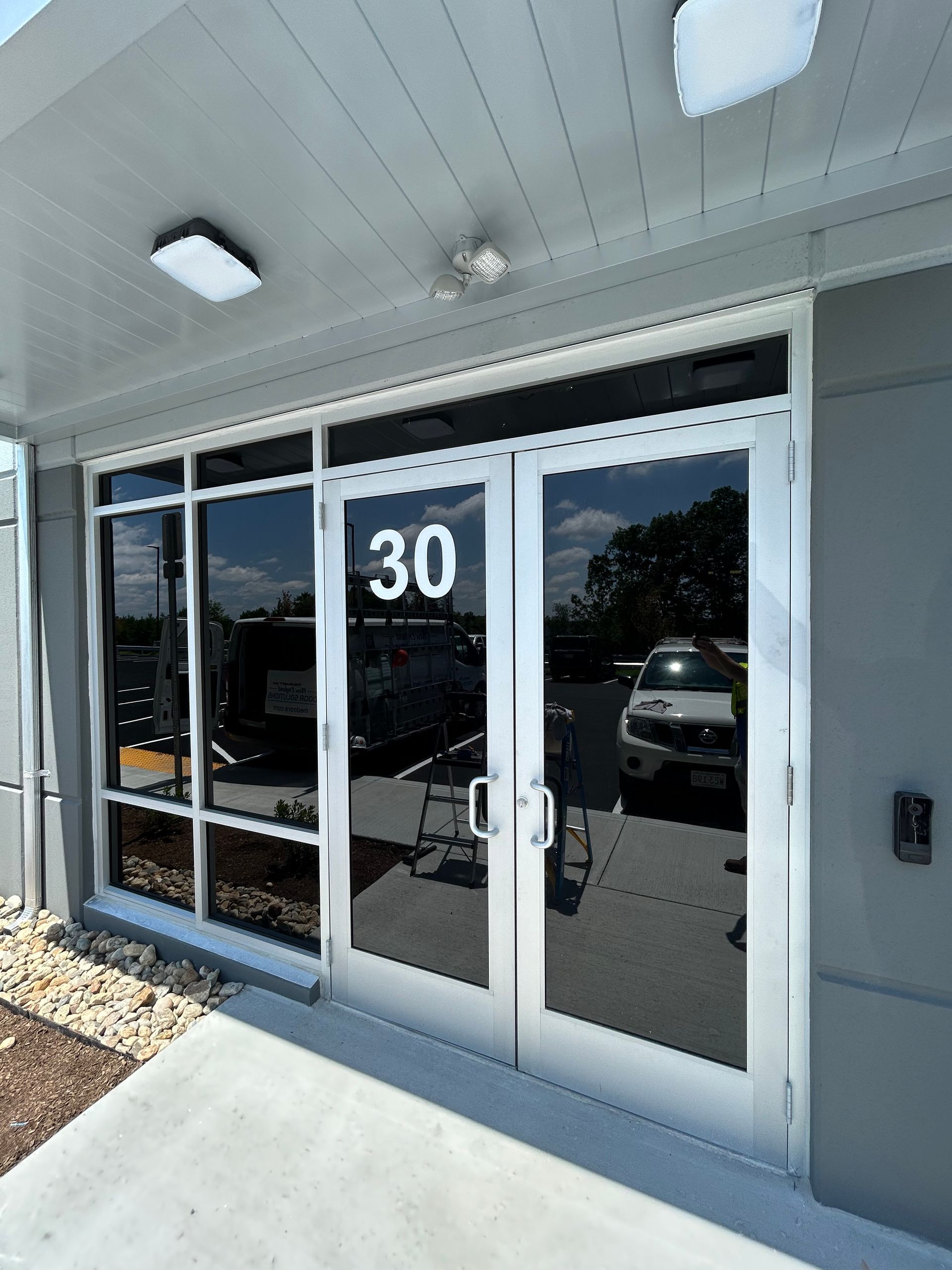 Exterior of building entrance, silver frame with tinted windows. Number 30 above the double doors.