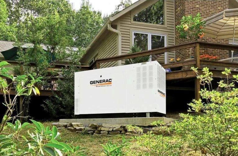 White Generac backup generator beside a house on a wooded hillside