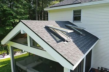 Back of house roof with two skylights and a white gable over a screened porch