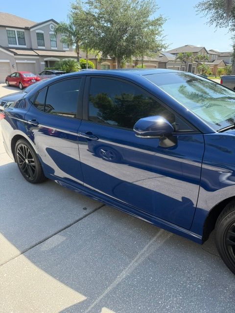 Blue sedan parked in a suburban driveway under bright sunlight