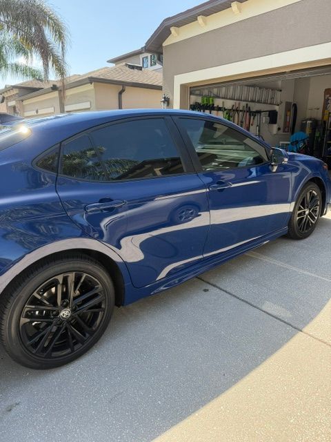 Blue Tesla Model Y parked in a driveway with an open garage behind it