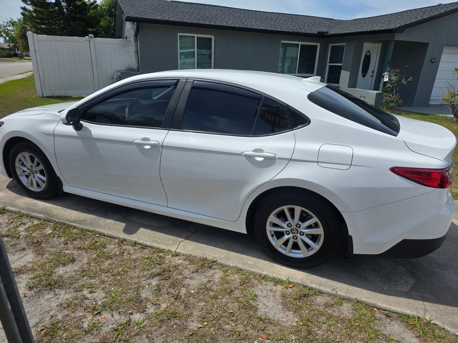 A white sedan parked on a driveway in front of a house