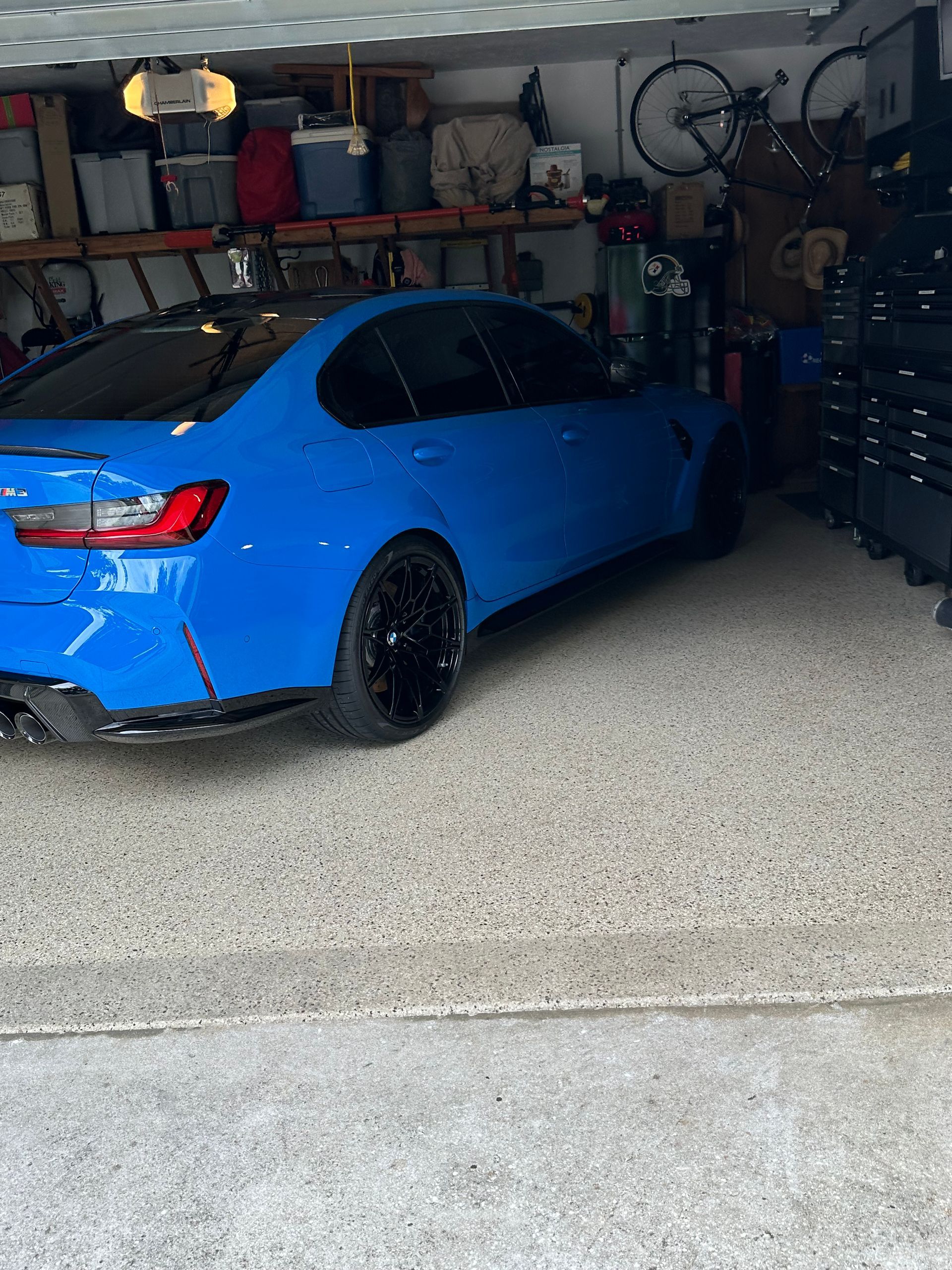 A blue BMW M3 is parked in a garage