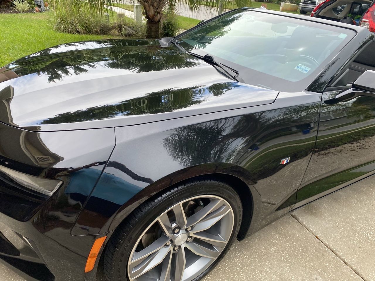 A black chevrolet camaro is parked in a driveway.
