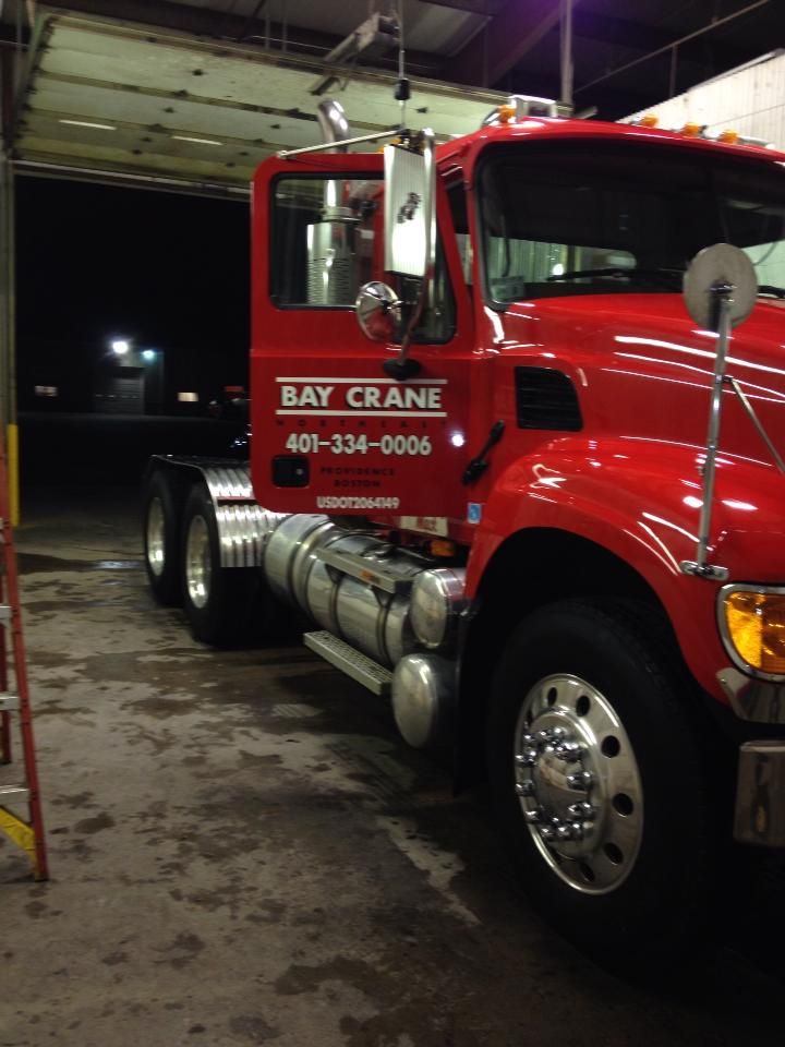 A red bay crane truck is parked in a garage