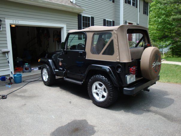 A black jeep is parked in front of a garage