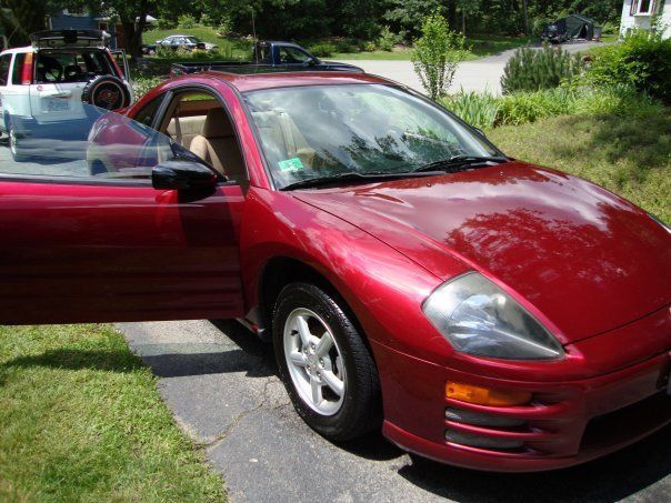 A red car is parked in a driveway with its doors open
