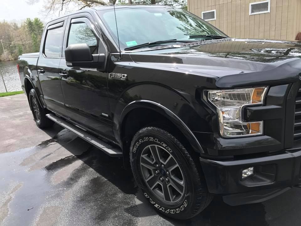 A black pickup truck is parked in a driveway next to a house.